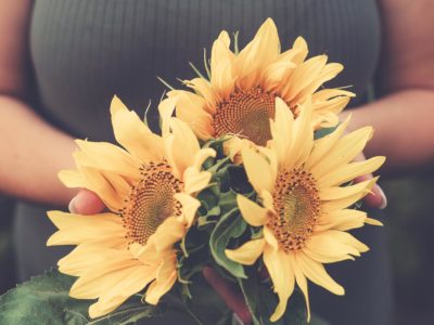 A woman holding a bouquet of sunflowers.