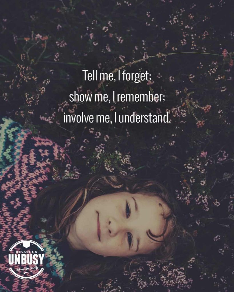 A young girl laying face forward in a field of flowers with a quote written overtop reading, "Tell me, I forget; show me, I remember; involve me, I understand."