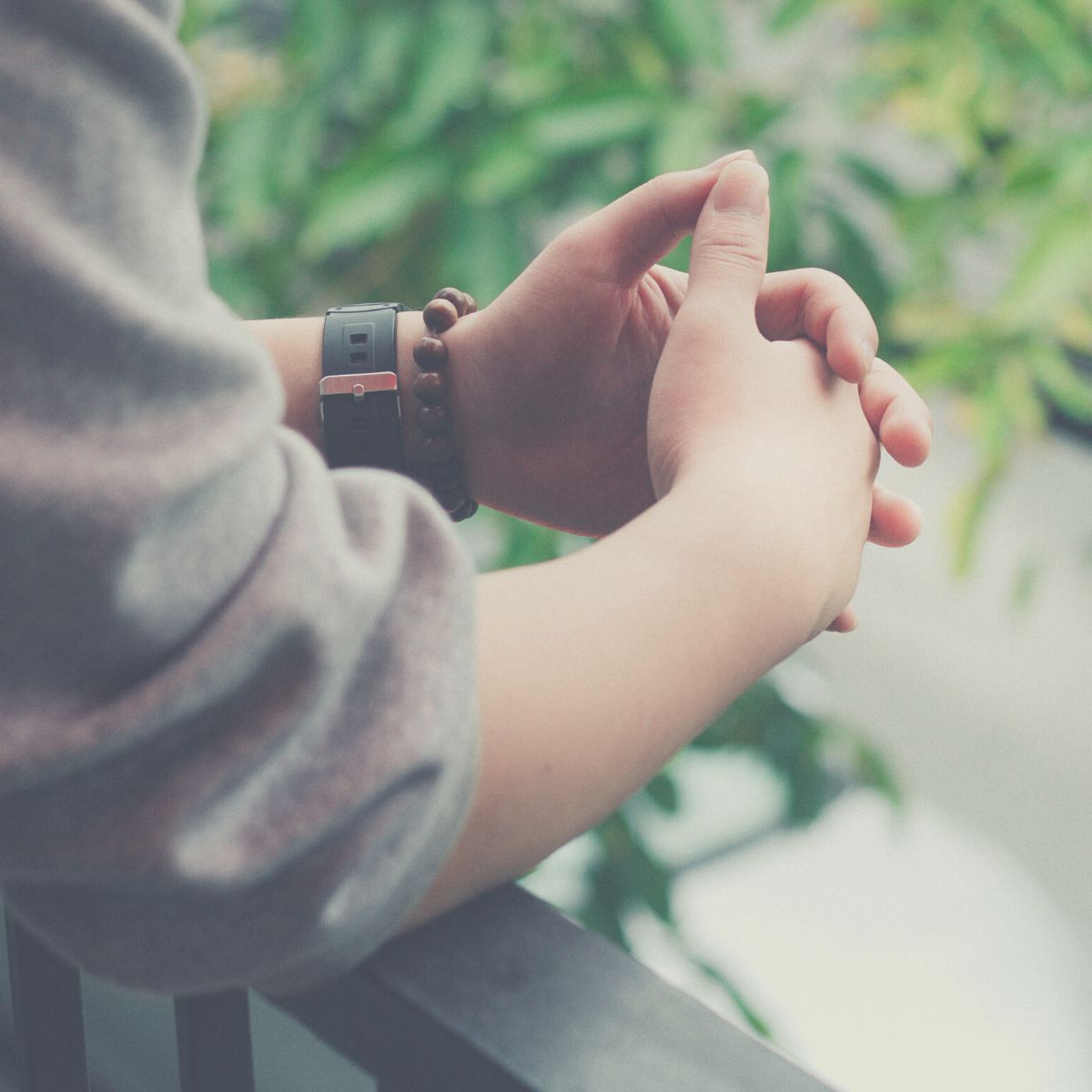 Woman clasping her hands and reflecting.