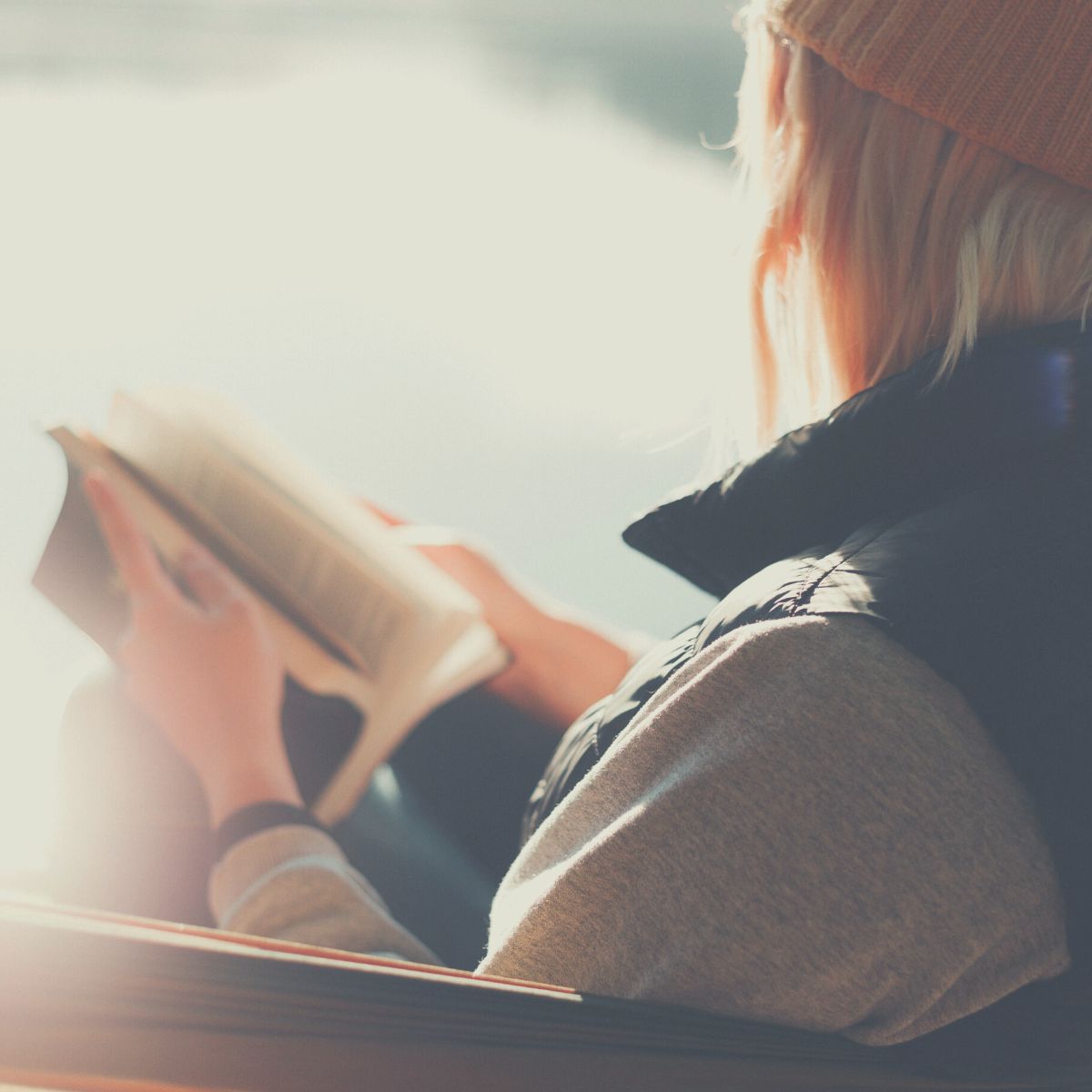 A woman pausing to think as she holds a book.