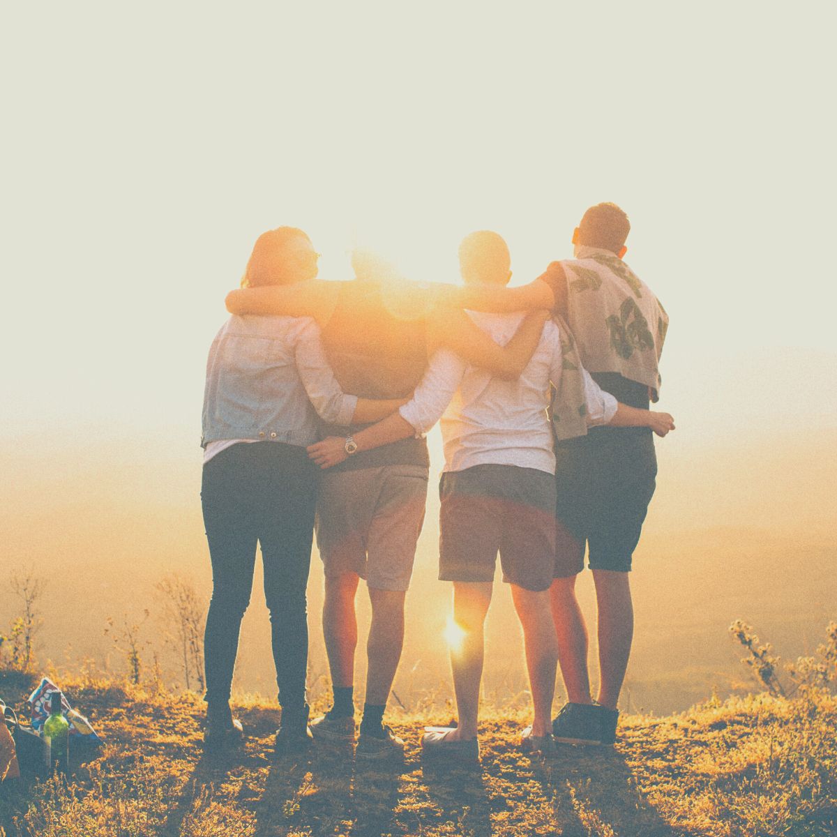 Group of enthusiastic people on an adventure with their arms around each others shoulders.