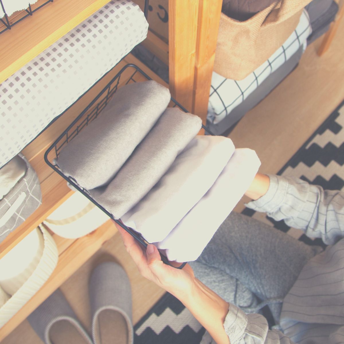 Organized woman pulling out a basket of folded sheets.