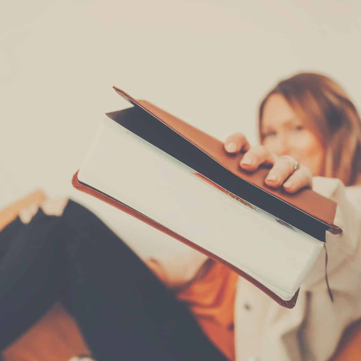 A woman holding out a poetry book for you to take.