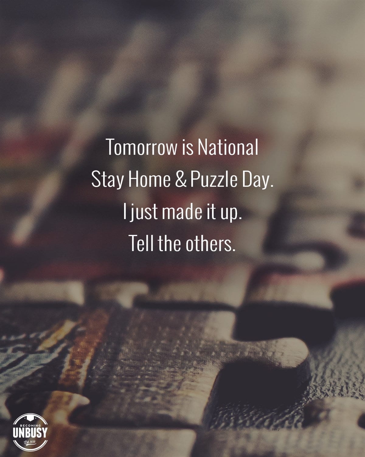 Close up of a puzzle with the following text written on top, "Tomorrow is National Stay Home & Puzzle Day. I just made it up. Tell the others.."