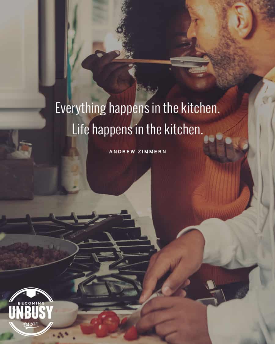 The following fall bucket list quote written over a photo of a woman holding a wooden spoon over a simmer pot for her partner to taste a new autumn recipe, "Everything happens in the kitchen. Life happens in the kitchen."