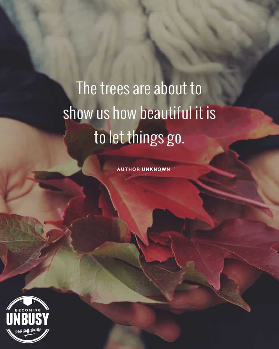 The following fall bucket list quote written over a photo of a woman wearing a knit scarf holding a collection of autumn leaves in her hands, "The trees are about to show us how beautiful it is to let things go."