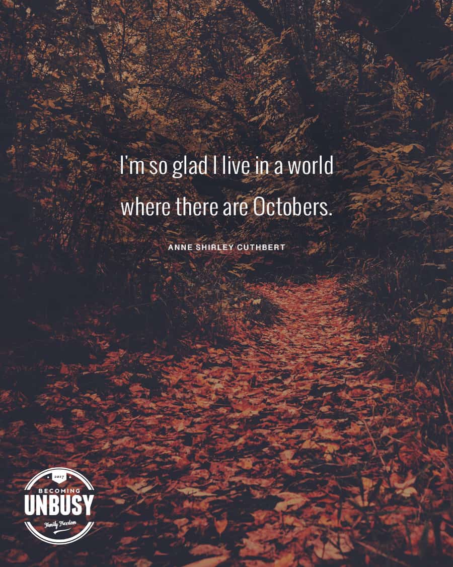 The following fall bucket list quote written over a photo of a path in the woods covered with autumn leaves, "I'm so glad I like in a world where there are Octobers."