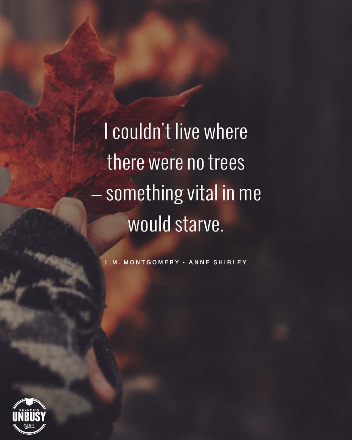 The following fall bucket list quote written over a photo of a woman wearing a chunky autumn sweater holding a single fall leaf, "I couldn't live where there were no trees — something vital in me would starve."