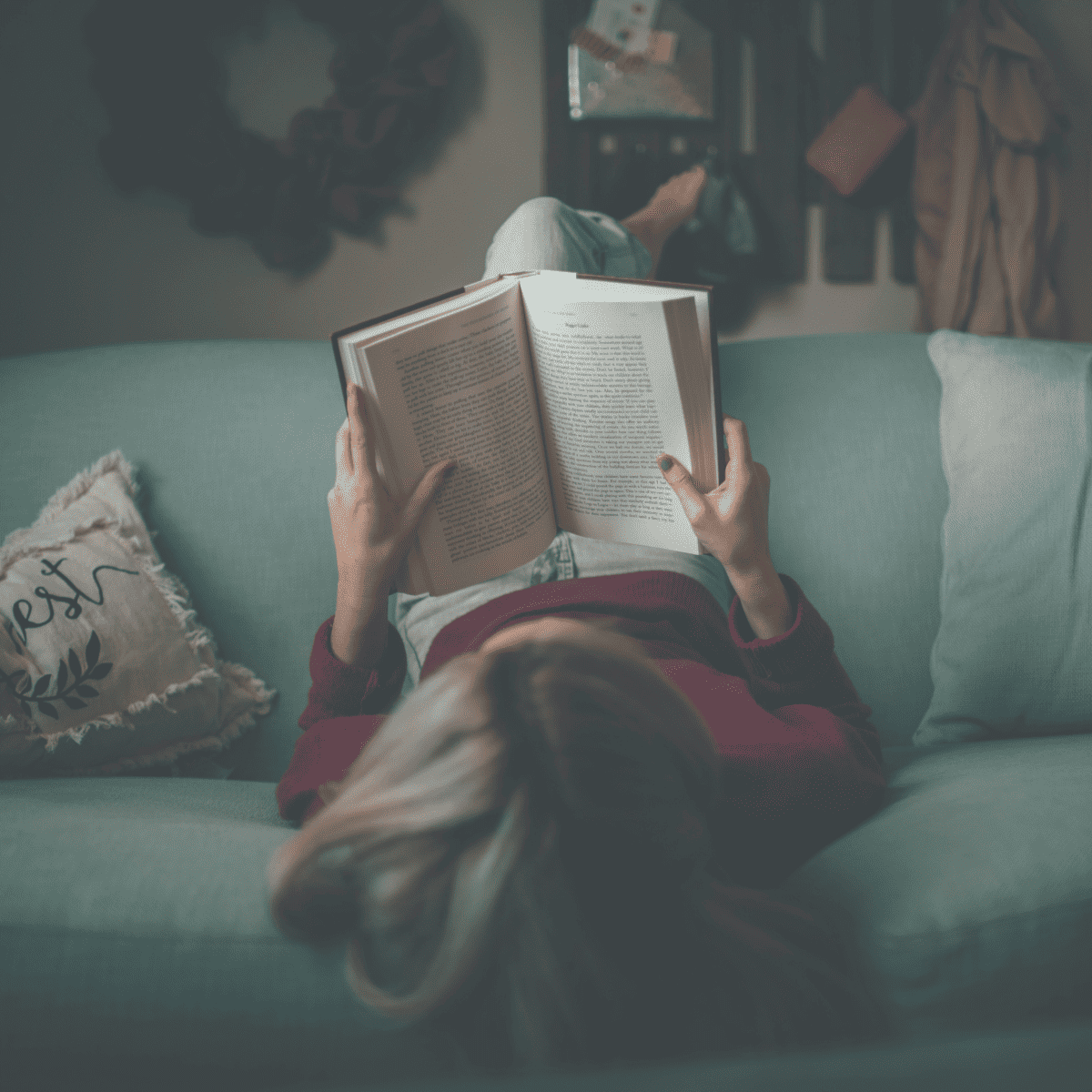 Woman embracing the JOMO as she reads a book on a couch.